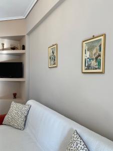 a living room with a white couch and a tv at Mpanos Sea Apartment 2 in Loutra Oraias Elenis