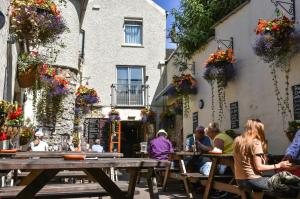 un grupo de personas sentadas en mesas fuera de un edificio en The Normandie en Tenby