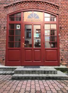 czerwone drzwi na ceglanym budynku w obiekcie Hostel Orange w Toruniu