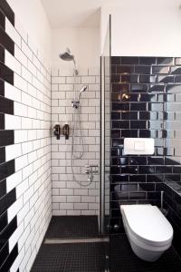 La salle de bains est pourvue de toilettes et d'une douche avec du carrelage noir et blanc. dans l'établissement Guesthouse fürDich, à Zurich