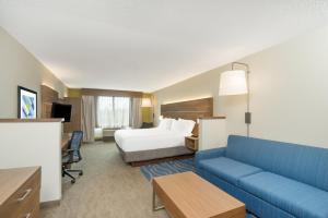 a hotel room with a bed and a blue couch at Holiday Inn Express Hotel & Suites Frankfort by IHG in Frankfort