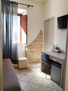 a room with a desk and a bed and a window at Camera ideale tra mare e montagna in Baunei