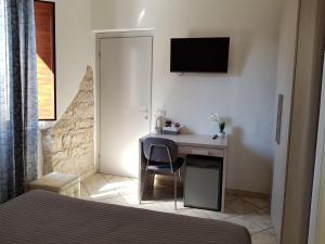 a bedroom with a desk with a bed and a television at Camera ideale tra mare e montagna in Baunei