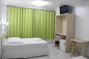 a bedroom with a bed and a green curtain at Oasis Chartouni Hotel in Blumenau