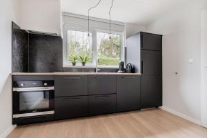 een keuken met een zwarte koelkast en een spoelbak bij vakantiehuis Seaside, Dunoweg 18 in Oostkapelle +14 foto's