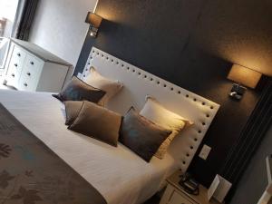 a bedroom with a large bed with four pillows at Le Trophée By M Hôtel Spa in Deauville