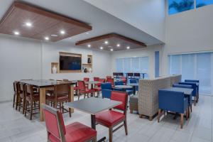 a dining room with tables and chairs and a tv at Holiday Inn Express Hotel & Suites Fort Lauderdale Airport/Cruise Port, an IHG Hotel in Fort Lauderdale