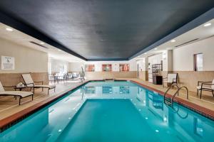 uma piscina num hotel com cadeiras e mesas em Holiday Inn Express and Suites Oklahoma City North, an IHG Hotel em Oklahoma City