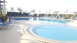 The Resort Chalet- Porto New Cairo في القاهرة: مسبح كبير وكراسي زرقاء ومسبح