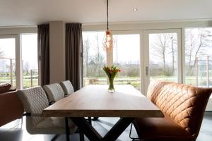 a dining room table with chairs and a vase of flowers on it at Ruyge Weyde Logies - The Farmers Daughter in Oudewater