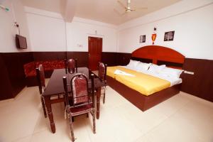 a bedroom with a bed and a table and chairs at Kairali Tourist Home in Guruvāyūr +37 photos
