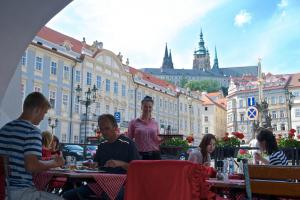 un grupo de personas sentadas en las mesas frente a los edificios en Residence U Mecenáše, en Praga