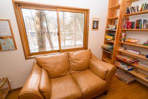 ein Ledersofa im Wohnzimmer mit Fenster in der Unterkunft Guest House Chaconne Karuizawa in Karuizawa