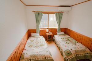 2 Betten in einem Zimmer mit Fenster in der Unterkunft Guest House Chaconne Karuizawa in Karuizawa