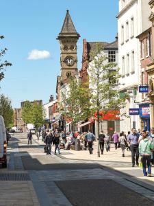 a busy city street with a clock tower at 6Adelphi in Preston