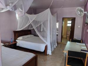 a bedroom with two beds with a mosquito net at Kambua Resort in Libwezi