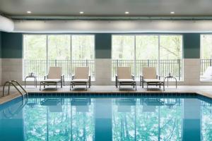 uma piscina num hotel com cadeiras e janelas em Holiday Inn Express - Auburn Hills South, an IHG Hotel em Auburn Hills