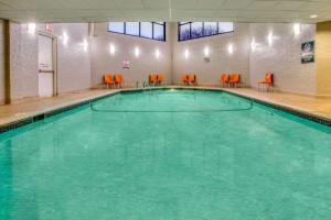 una gran piscina con sillas naranjas en un edificio en La Quinta by Wyndham Minneapolis Bloomington W en Bloomington