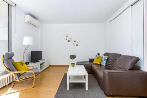 a living room with a brown leather couch and a table at Lodging Apartments Beach Apartment Villa Olimpica in Barcelona