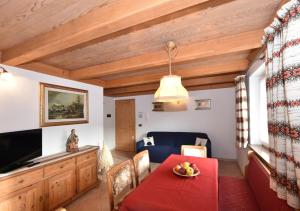 un salon avec une table rouge et une télévision dans l'établissement Villa Mirabell, à Cavalese