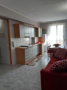 ein Wohnzimmer mit einem roten Sofa und einer Küche in der Unterkunft Casa Vacanze Ottantapassi in Otranto