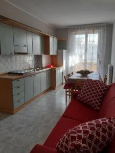 a living room with a red couch and a kitchen at Casa Vacanze Ottantapassi in Otranto