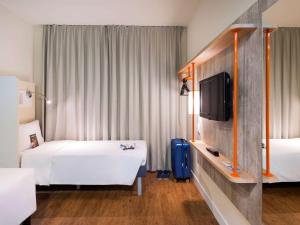 Habitación de hotel con 2 camas y TV en ibis budget Navegantes Itajai en Itajaí
