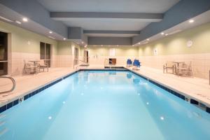 een groot zwembad in een fitnessruimte met stoelen en tafels bij Holiday Inn Express & Suites - Sterling, an IHG Hotel in Sterling