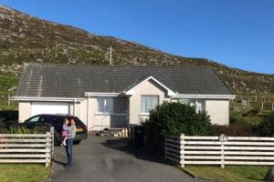 a woman standing next to a car in front of a house at SOLACE COTTAGE in Bunaveneadar