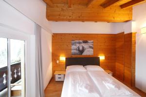 a bedroom with a white bed with a wooden wall at Edelweiss am See in Zell am See