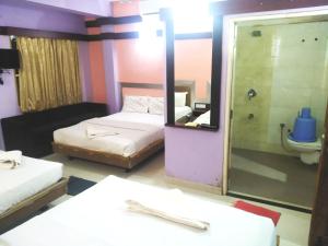 a room with two beds and a mirror and a toilet at Abimon Residency Kollur in Kollūru