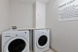 a white laundry room with a washer and dryer at Holiday Inn Express Hotel & Suites Eugene Downtown - University, an IHG Hotel in Eugene