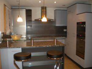 a kitchen with a counter and two stools in it at Chalet uf em Stutz 2 in Grindelwald +19 photos