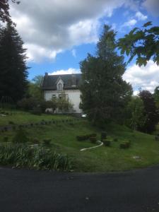 a large white house with a yard with trees at haras de la Cère ses chevaux et Harley Davidson garage in Polminhac