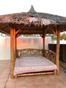 a bed under a wooden gazebo on a patio at Casa Maria Sunset in Cala Vadella