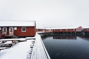 a building and a river with snow on the ground at Lofoten Cabin and Kayak Rental in Stamsund