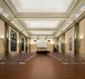 an empty hall with chairs and a projection screen at I Portici Hotel Bologna in Bologna