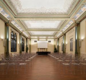 eine leere Halle mit Stühlen und einer Leinwand in der Unterkunft I Portici Hotel Bologna in Bologna