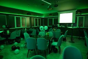 una sala de conferencias con sillas verdes y una pantalla en Harmony Hotel, en Kumanovo