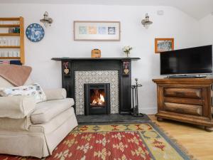 ein Wohnzimmer mit Kamin und Fernseher in der Unterkunft Rosa Cottage in Porthleven