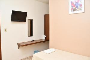 a room with a bed and a tv on the wall at Hotel Alphard in Várzea Grande