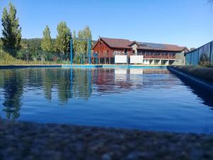 una piscina de agua con una casa en el fondo en Eco Hotel Antuco en Antuco