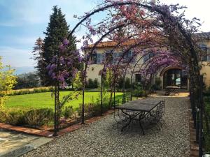 a garden with a picnic table under an arch with purple flowers at Villa Medicea di Lilliano in Grassina