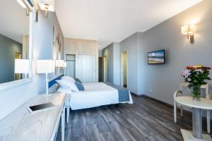 a room with a bed, a chair, a table and a lamp at Apartamentos Colón Playa in Las Palmas de Gran Canaria