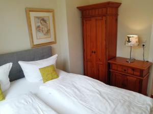 a bedroom with a white bed and a wooden cabinet at Waldhotel Forsthaus Remstecken in Koblenz