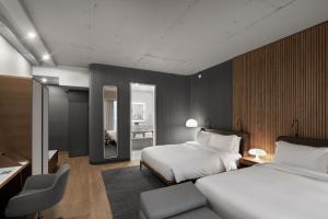 a hotel room with two beds and a chair at Hôtel Le Germain Montréal in Montreal