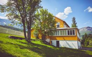 una casa amarilla y blanca en una colina con árboles en Sommerhotellet en Vang I Valdres