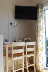 mesa de comedor con 2 sillas y TV en la pared en Marbury Camp and Lodge, en Whitchurch