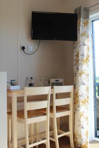 a dining room table with two chairs and a television on the wall at Marbury Camp and Lodge in Whitchurch