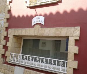 un balcón de un edificio con un cartel en Apartamentos Turísticos Las Saladas, en Chiprana